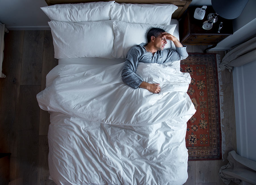 man-on-bed-with-a-headache-A2WGP74